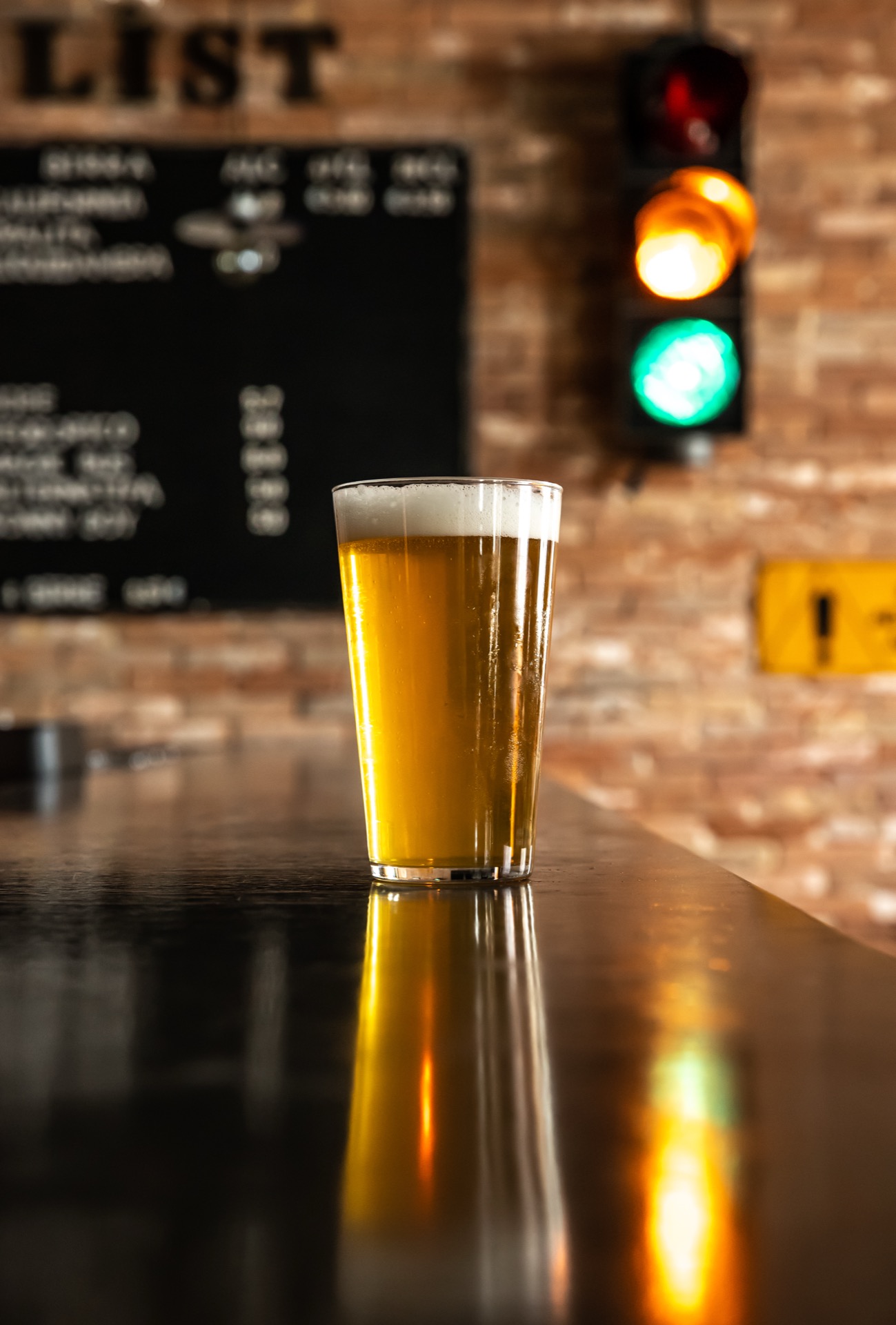 Pint of craft beer on a bar counter, traffic light blurred in background